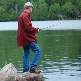 Man stan ding on rock fishing