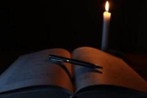 Pen on an open book with a candle