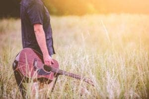 guitar player in a field of tall grass questioning his ability