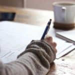 An arm and hand writing at a desk