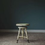 a lone stool against a blue wall