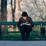 elderly lady on a bench reading