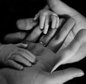 adult hands holding infants hand