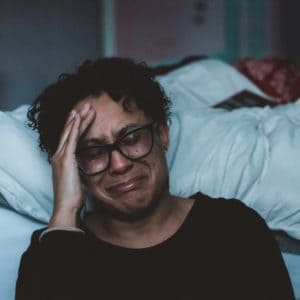 woman grieving with tears beside a bed