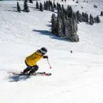 Man in yellow coat skiing downhill