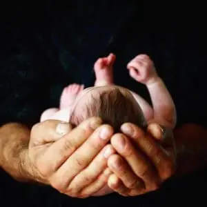 a newborn child cupped in two hands