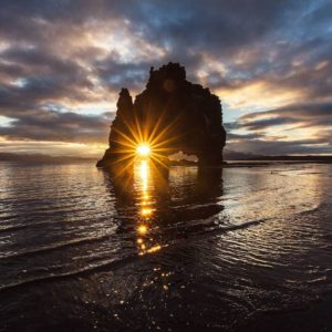 twinkling light in front of a rock in the sea