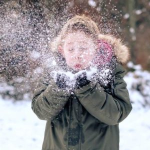 boy blowing snow flakes