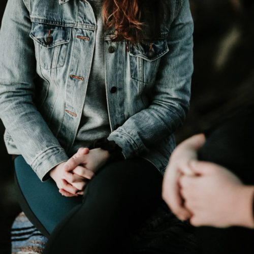 two people with clasped hands talking about death