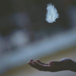 mystery illustrated by feather floating above an open hand