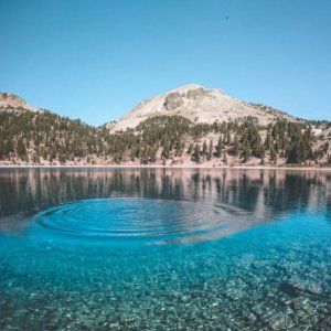 rings of wwater in a lake with mountains in the back