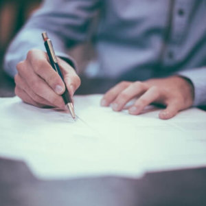 hands holding pen and paper while writing