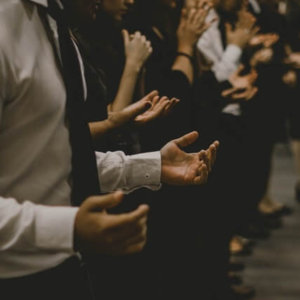 people in worship with open hands