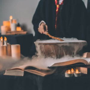 unseen person stirring a steamy pot surrounded by many candles as if it were a magic potion