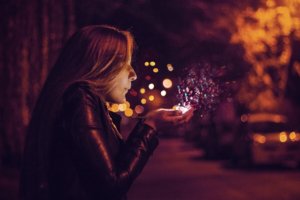 woman breathing upon magical lights in her hands, december declutter