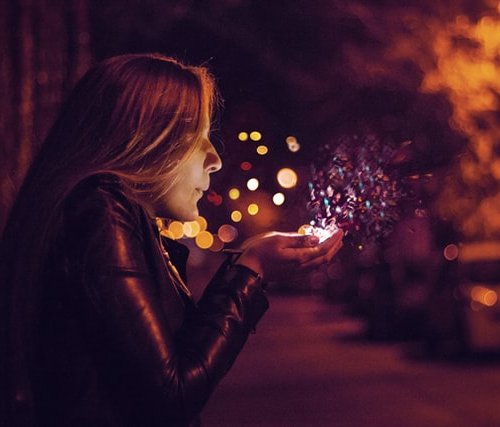 woman breathing upon magical lights in her hands, december declutter