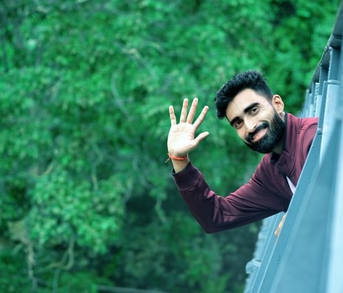 man waving hello and goodbye from a car window