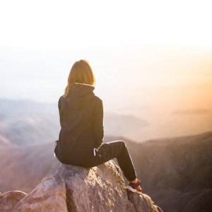 Woman sitting in the power of silence on a mournain peak wondering if she were religious